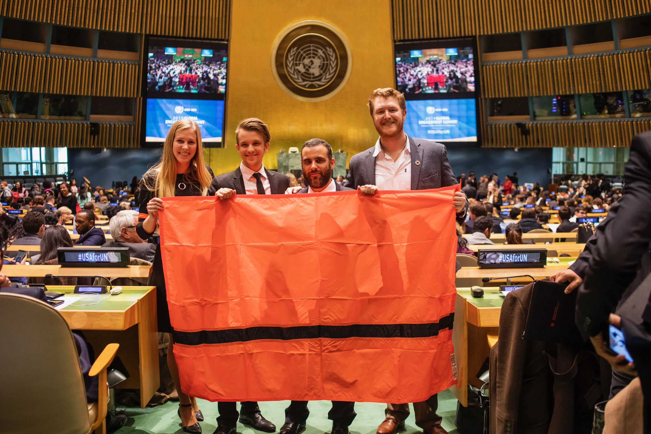 The IOR delegation can be seen holding a gift, the Refugee flag, from the Refugee Nation at the New York HQ, 2019 United Nations Global Engagement Summit. Pictured from left to right: Caroline Kurdej, Sebastian Agignoae, Juan Lazo Jr., Christopher Dowell.