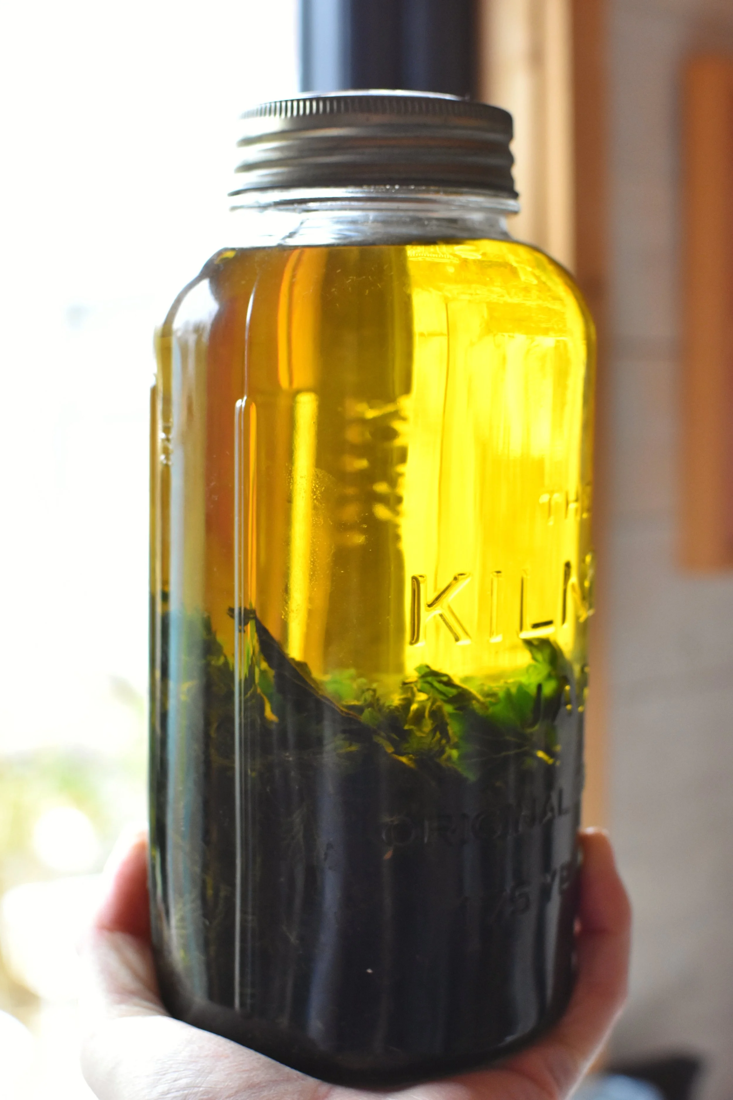a jar of nettle infused olive oil, an ingredient in Green Roots Hair and Scalp Oil from Naturally at the Wrens Nest