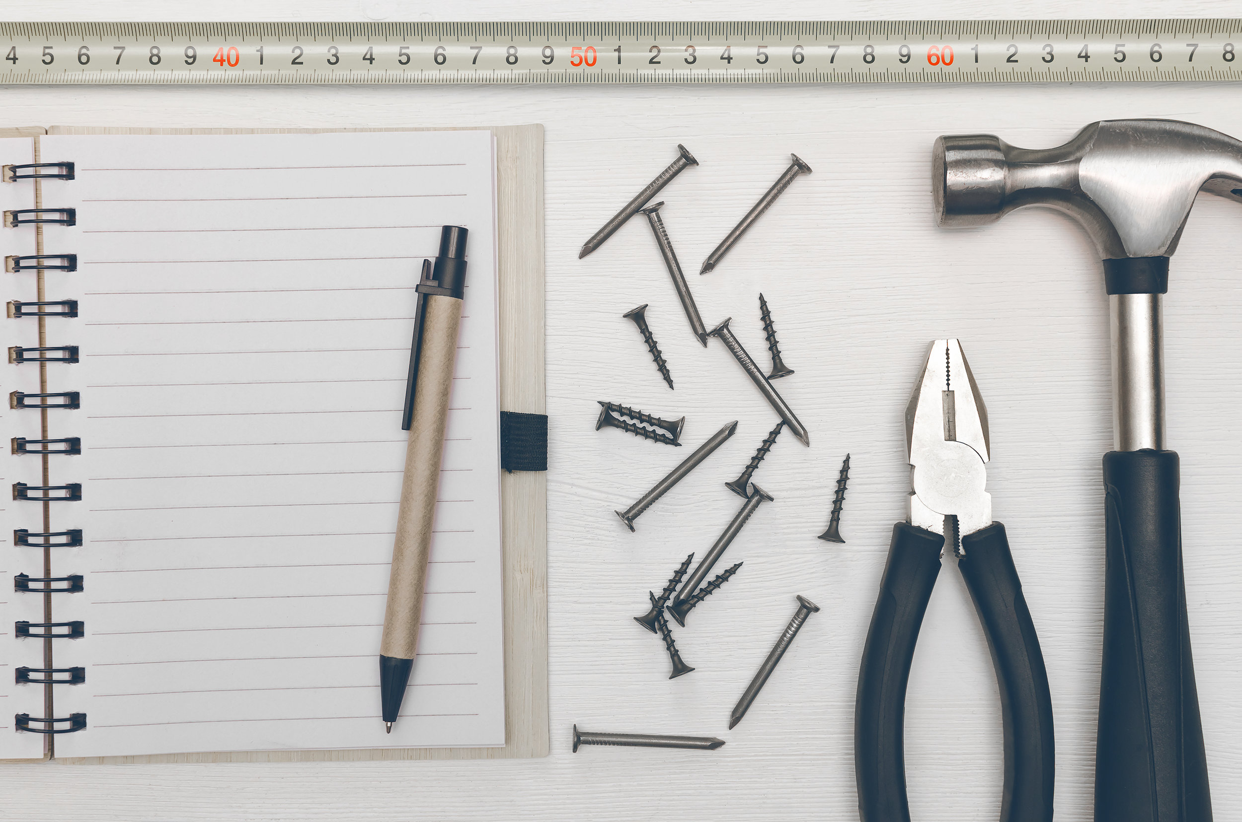 Blank-note-pad-with-empty-paper-sheet,-pen-and-hammer-with-nails-on-the-table.-Construction-tricks.-942878744_3020x2000 (1).jpeg