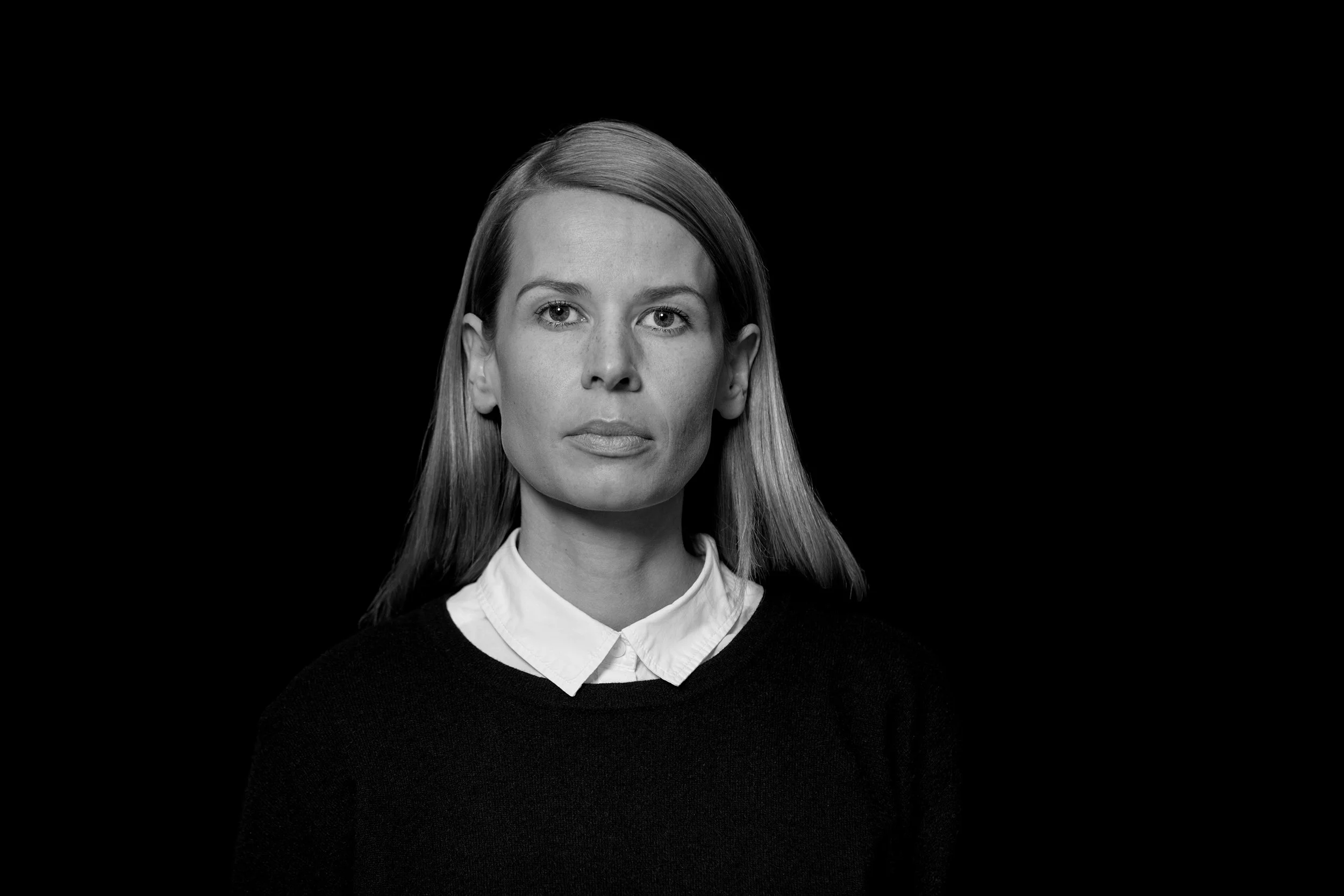 Schwarz weißes Portrait einer Frau vor dunklem Hintergrund, ruhig ausgeleuchtet im Fotostudio.