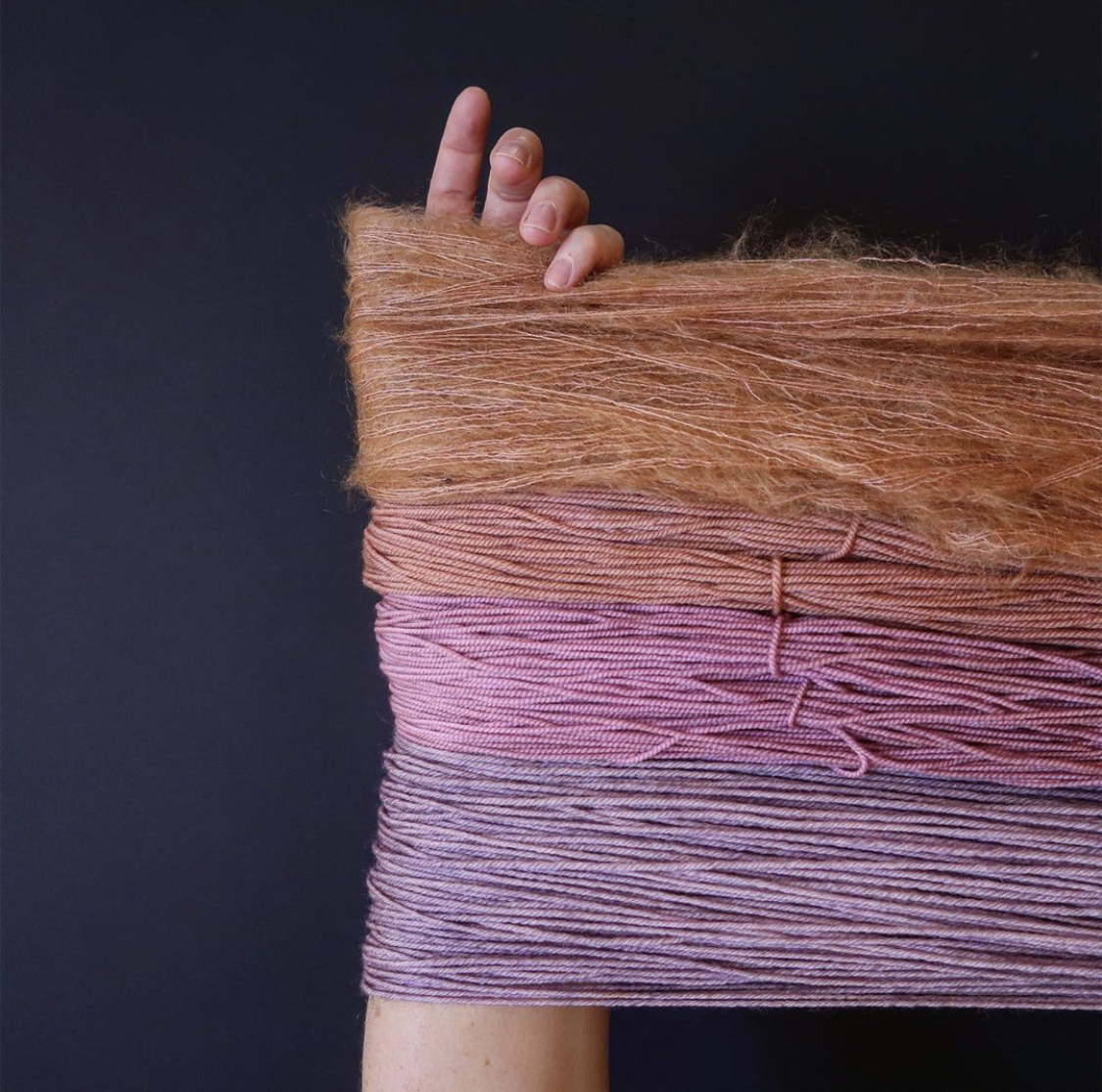 Four hanks of varying shades of pink yarn are stretched across Tayler’s arm; Photo by Tayler Earl of Fiber for the People®