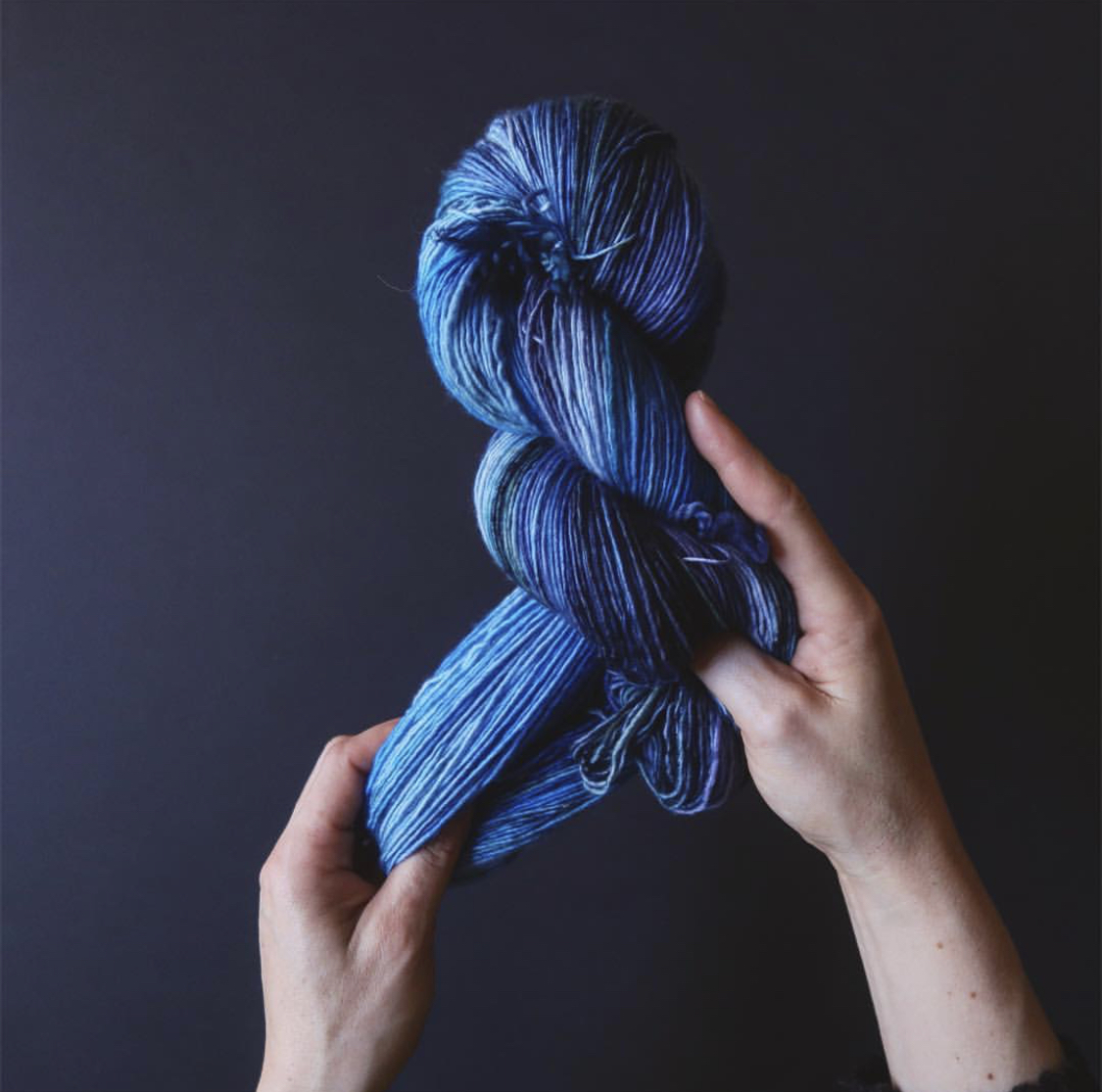 Tayler’s hands stretch out a beautiful blue tonal skein; Photo by Tayler Earl of Fiber for the People®