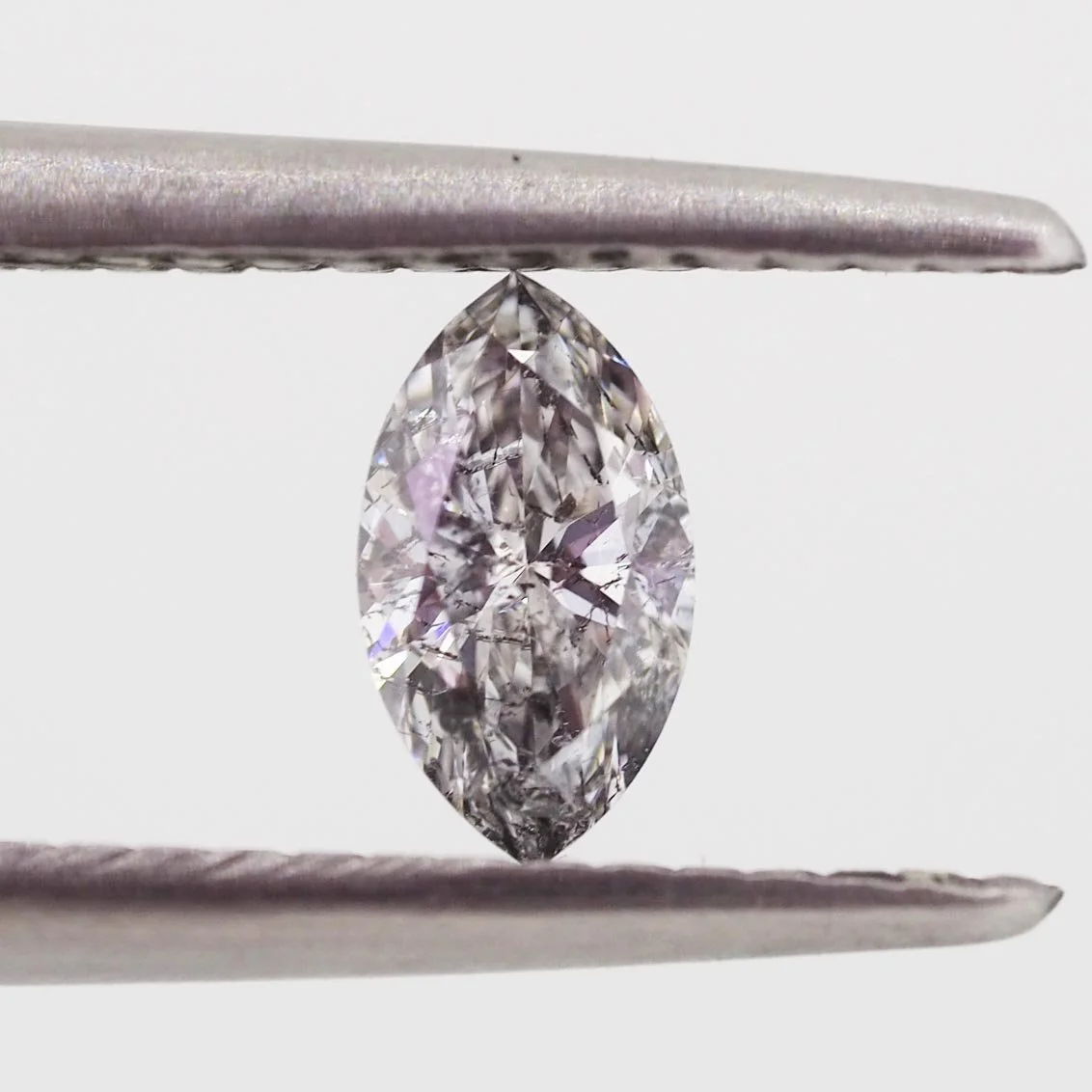 a marquise cut salt and pepper diamond held in tweezers
