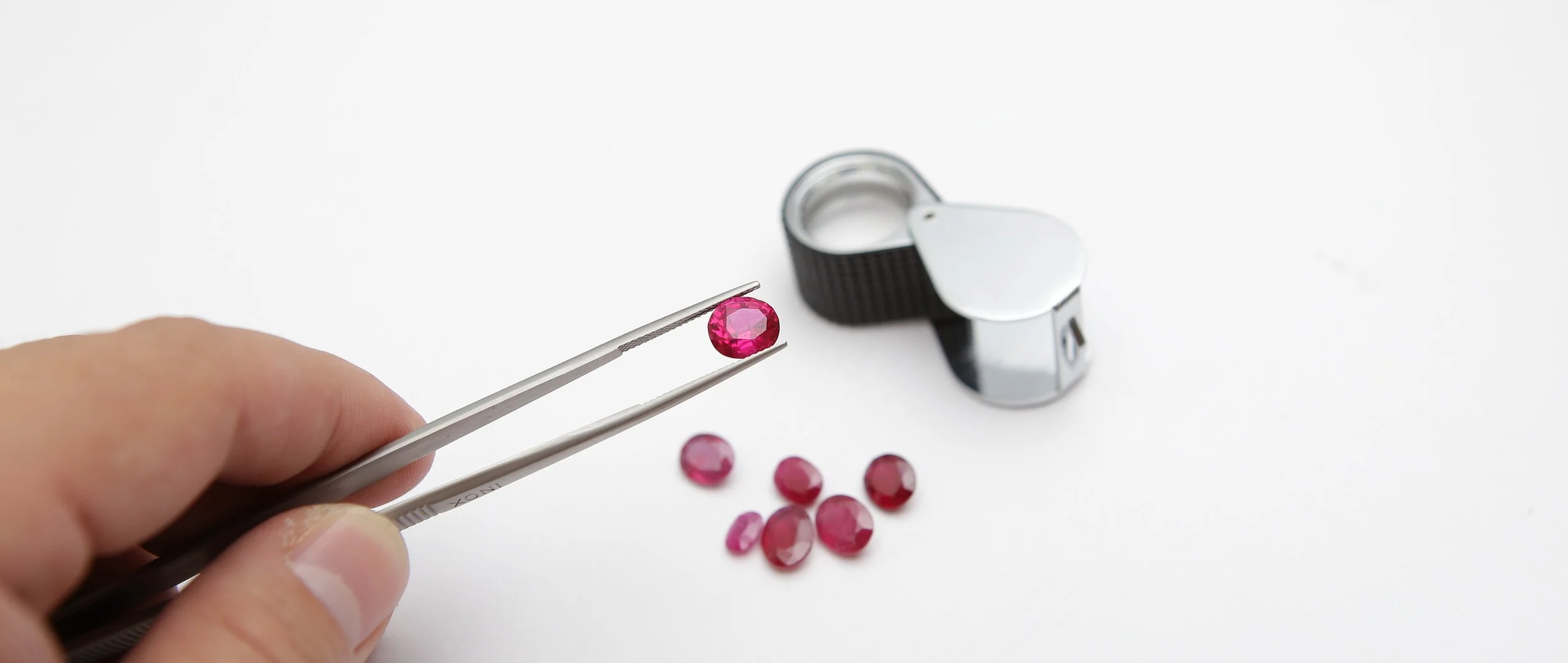 cut and polished ruby gemstones held in tweezers for inspection