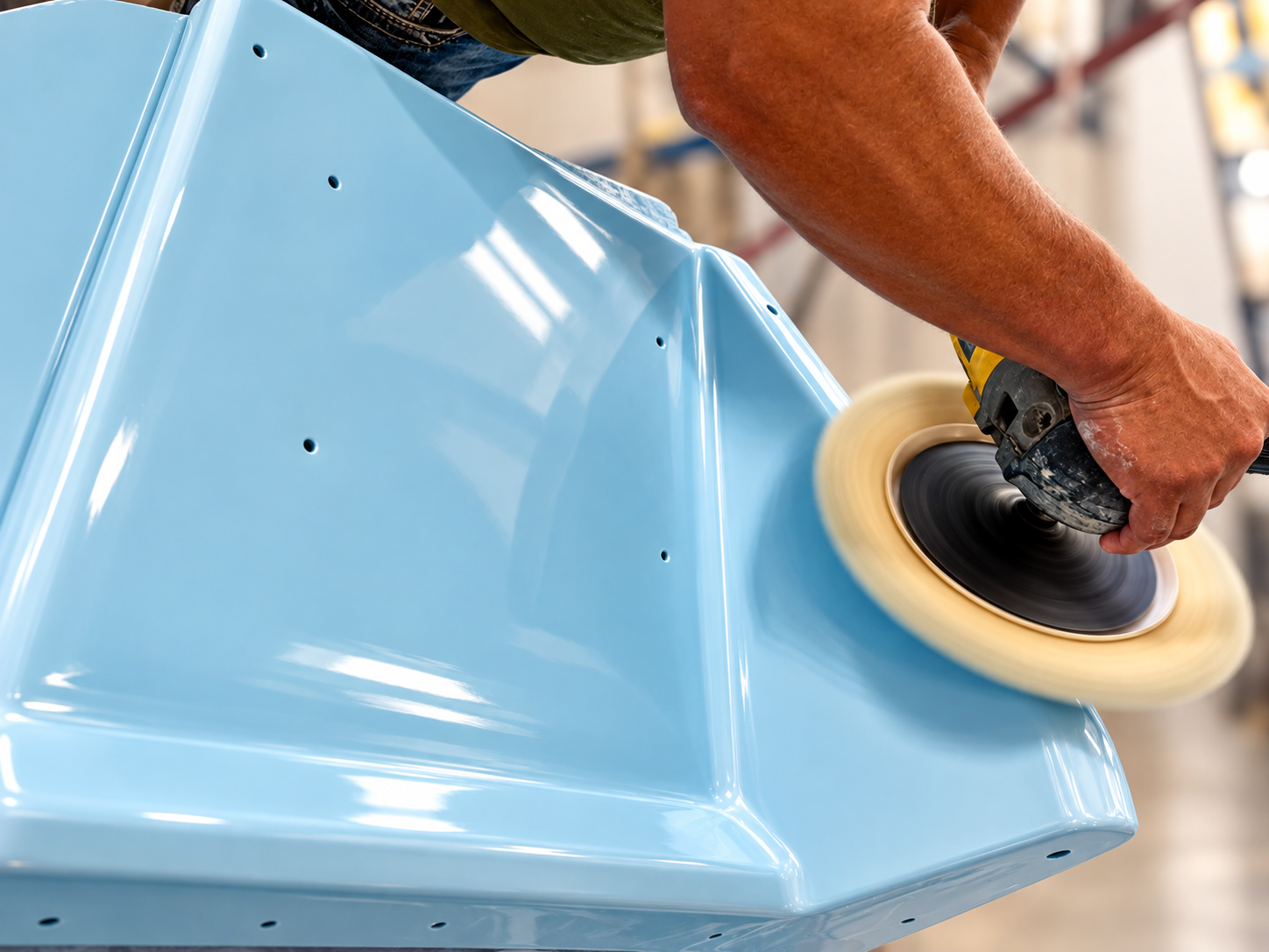 Technician polishing a light blue fiberglass boat surface during gelcoat restoration.