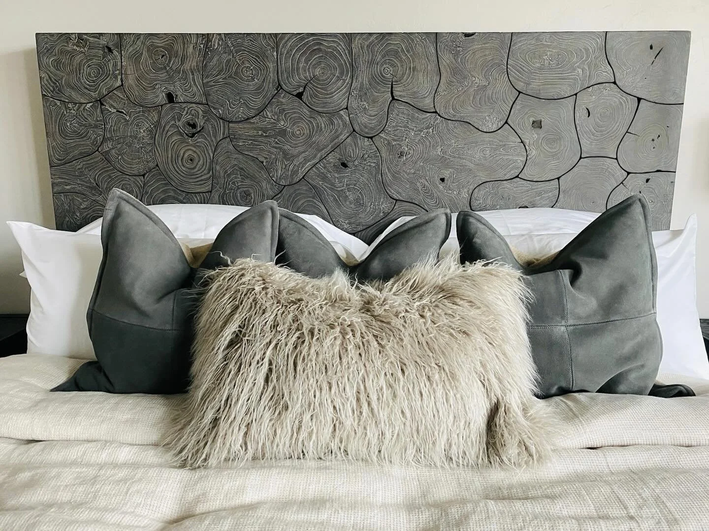 Absolutely love this detailed shot of the luxurious guest bedroom! The stunning wood bed with intricate, natural details adds such warmth and character to the space. Layered with plush suede pillows for a touch of masculinity and topped off with a fu