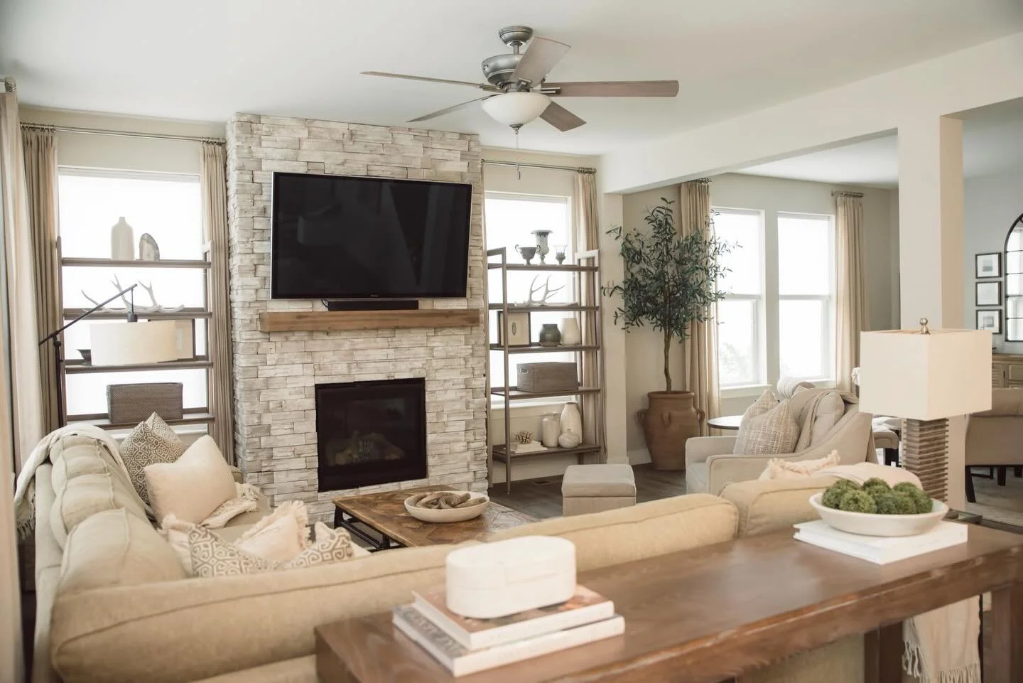 Soft neutrals, layered textures, and natural light 

This living space is all about calm, comfort, and effortless warmth. The stacked stone fireplace anchors the room while the soft textiles, warm woods, and organic accents keep everything feeling re