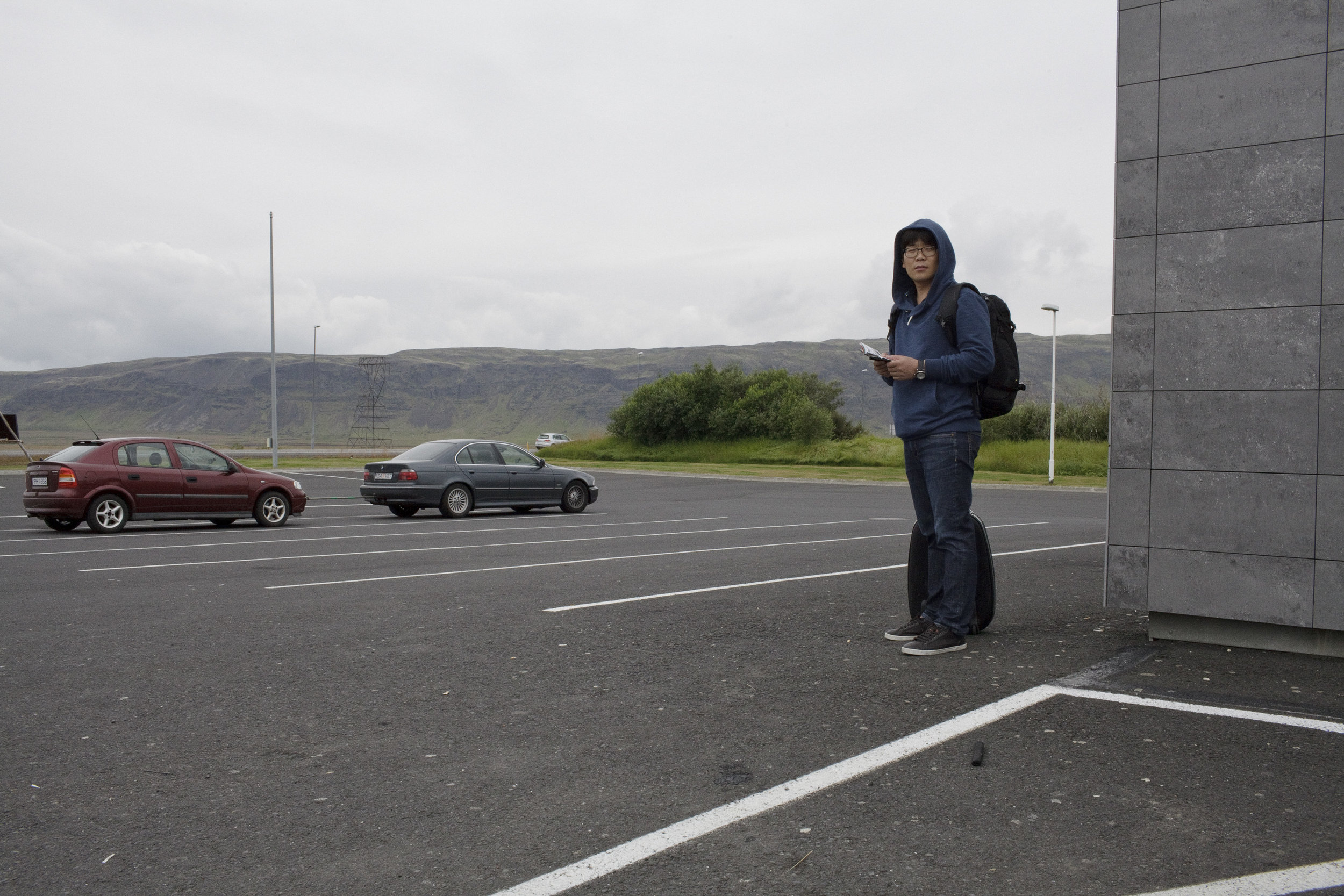 A tourist waits for the bus outside of a gas station in Hveragerdi.