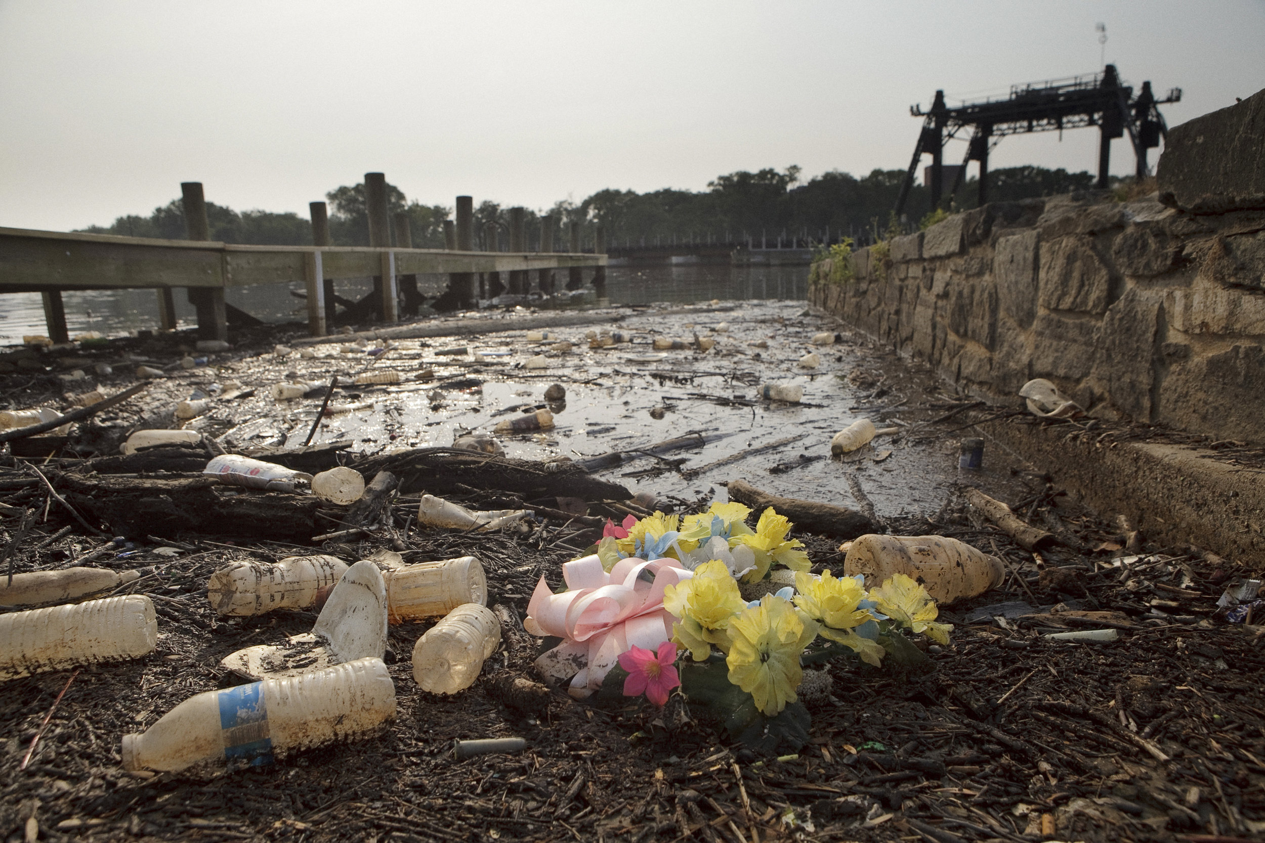  Rains often bring a great deal of trash to the surface of the river, here, what looks like a pristine funeral wreath is surrounded by washed up bottles and sticks. 