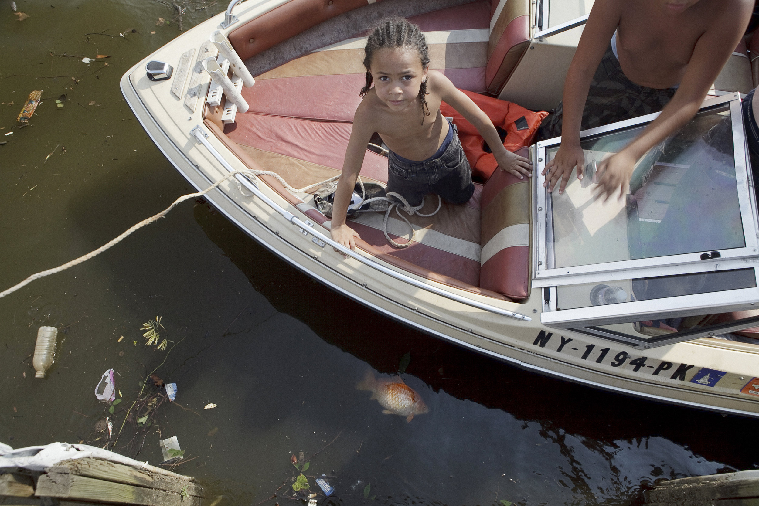  A boy rides on a recreational boat with his family, stopping by a pier in Anacostia Park.  