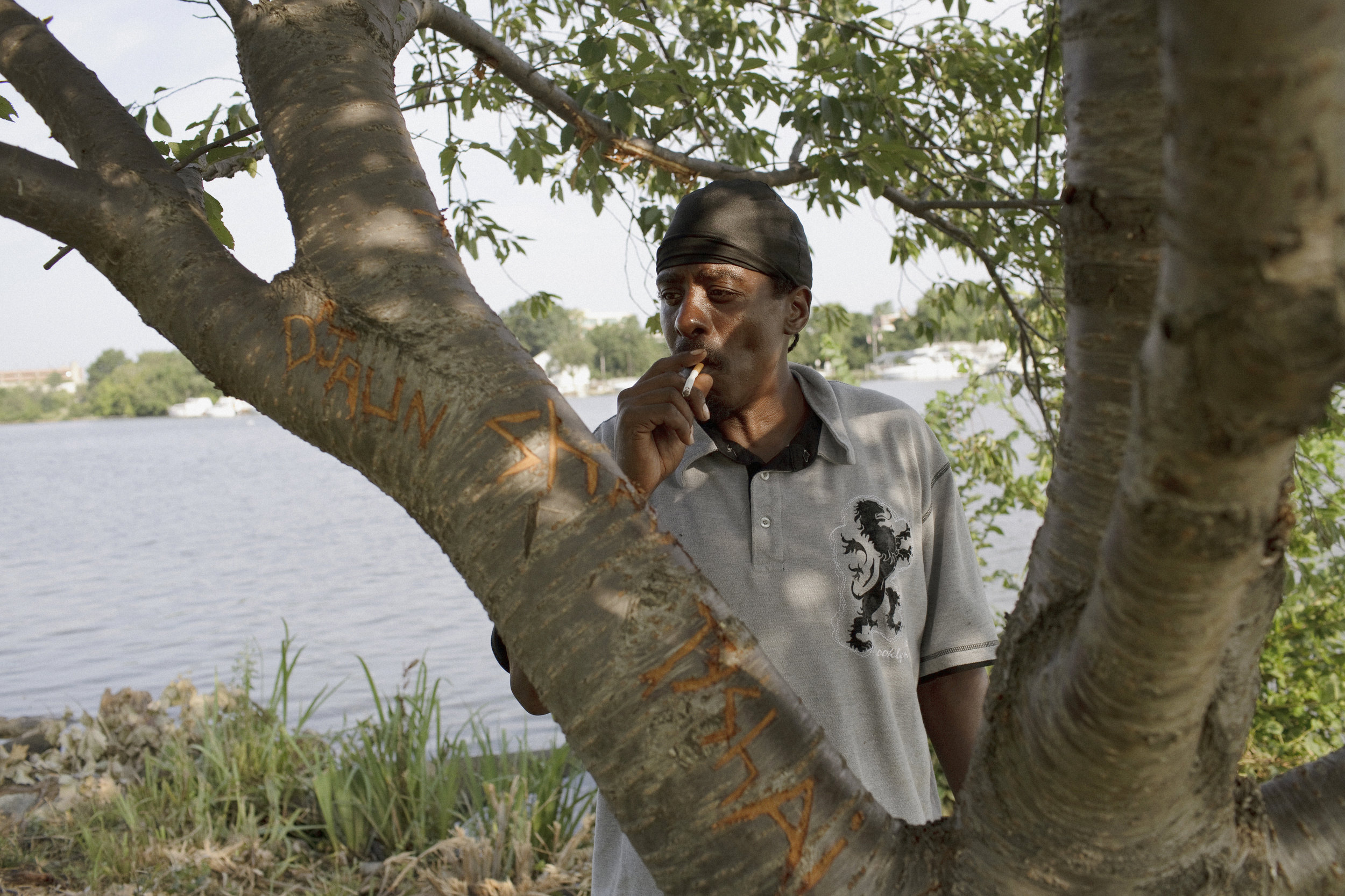 Wink, pictured here, and his best friend Earl routinely fish under this tree in Anacostia Park. Etched in the tree, D'Jaun is one of Wink's nine children, six of whom have their names carved here.