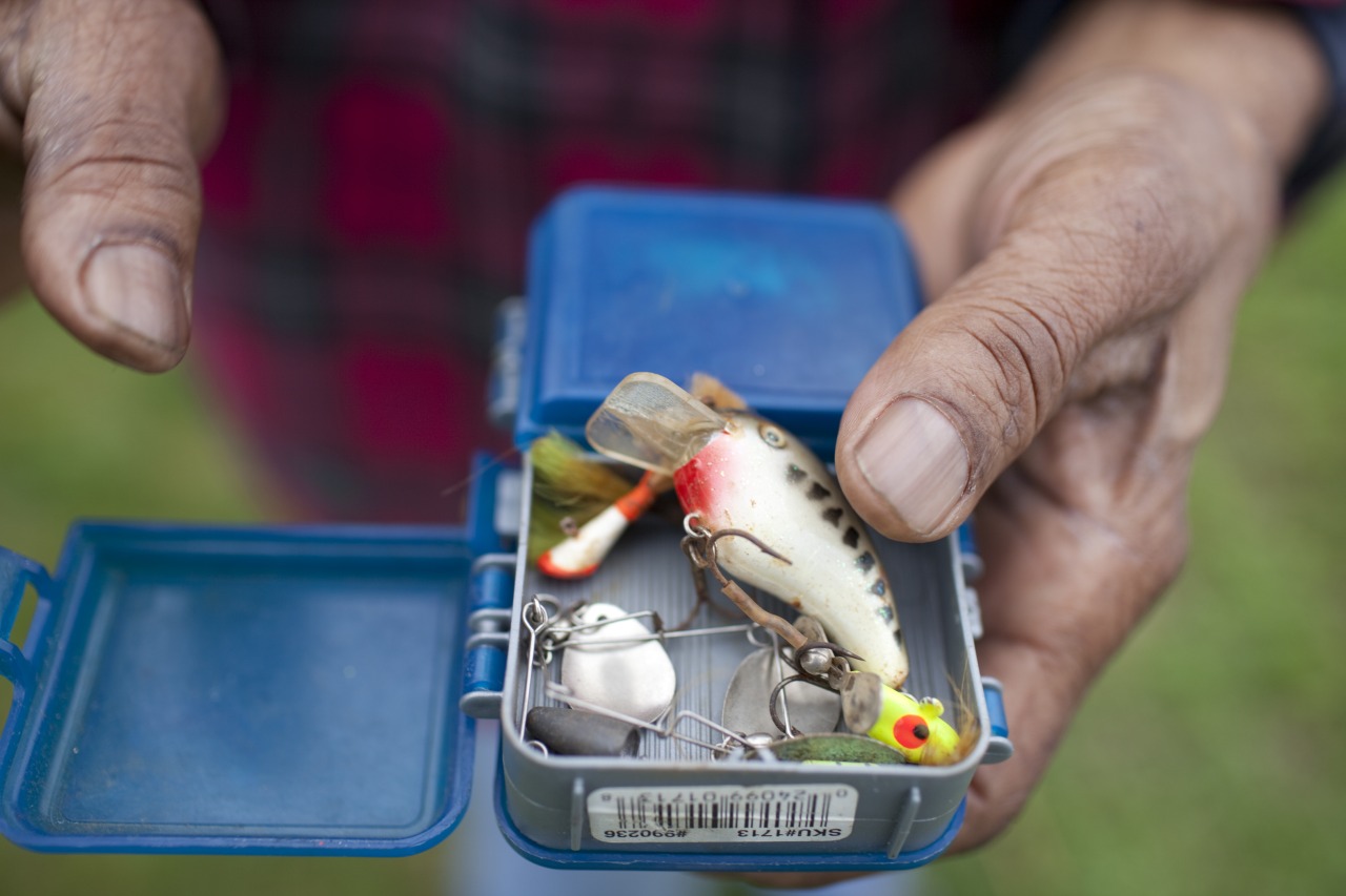  A man holds a tackle box as he fishes from the east bank of the Anacostia with his nephew. The two men didn’t plan to keep their catch for themselves, but to share it with friends in need.  