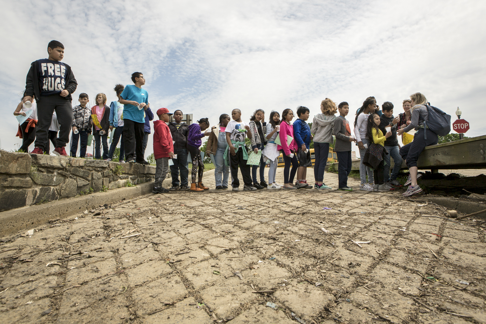 Students from Capitol City Public Charter school wait in line to fill a small cup with American shad fry, which they will then release into the river.