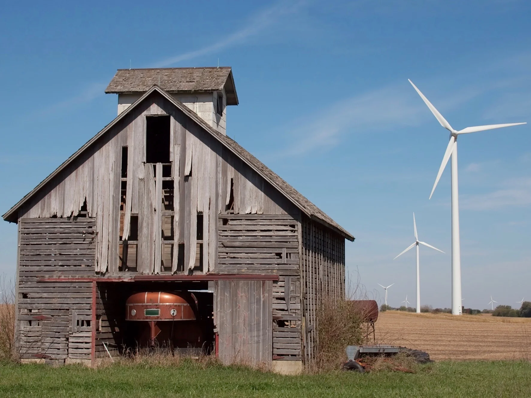 Wind turbines line up alongside an old barn in Illinois. (Wikimedia Commons/Dori)