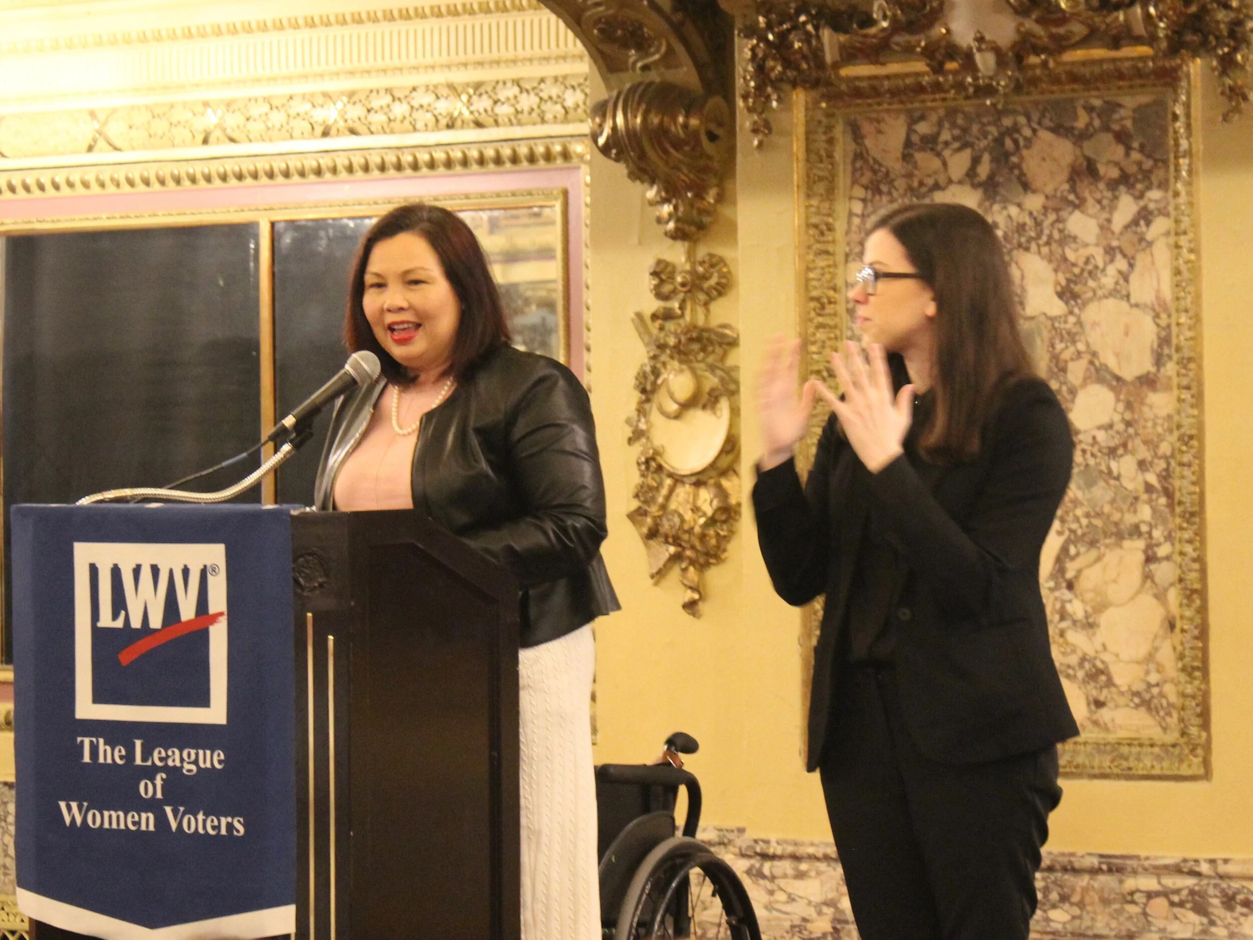 Joined onstage by a sign-language interpreter, Sen. Tammy Duckworth delivers remarks to the League of Women Voters of Illinois in the Gold Room of the Congress Plaza Hotel. (One Illinois/Ted Cox)