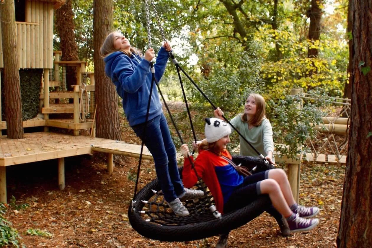 Three children swing on a Nest Swing