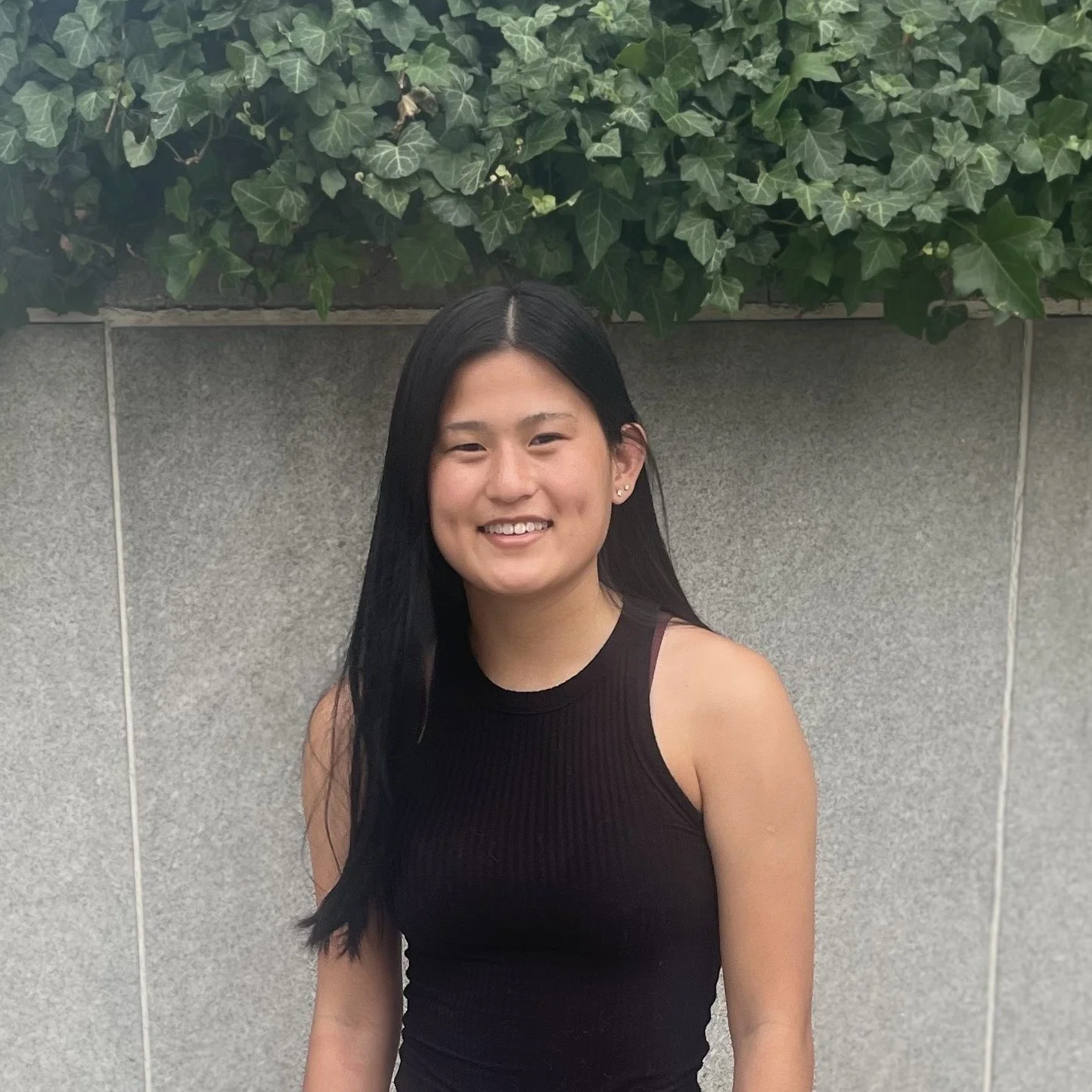 student with dark hair standing below ivy