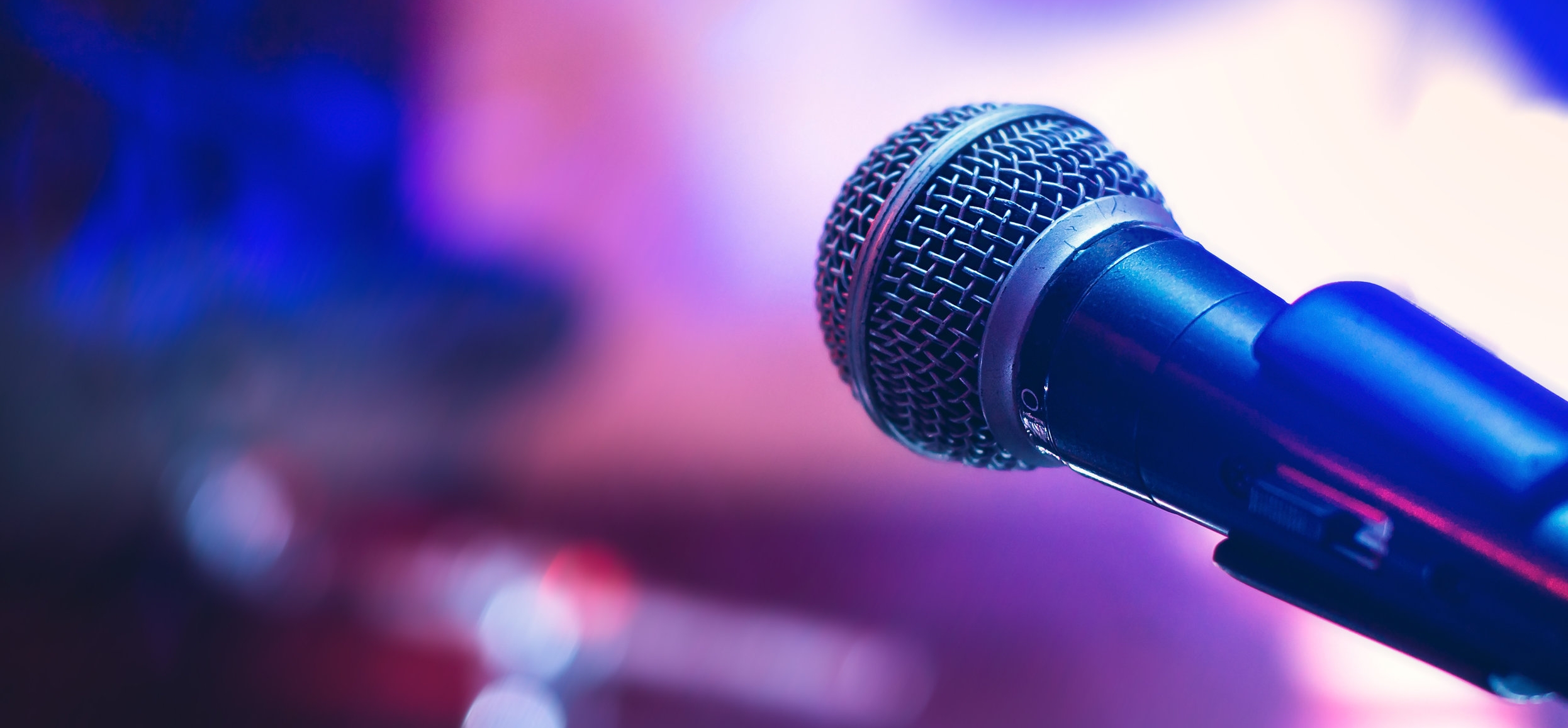 Image: A microphone in front of a purple background. 