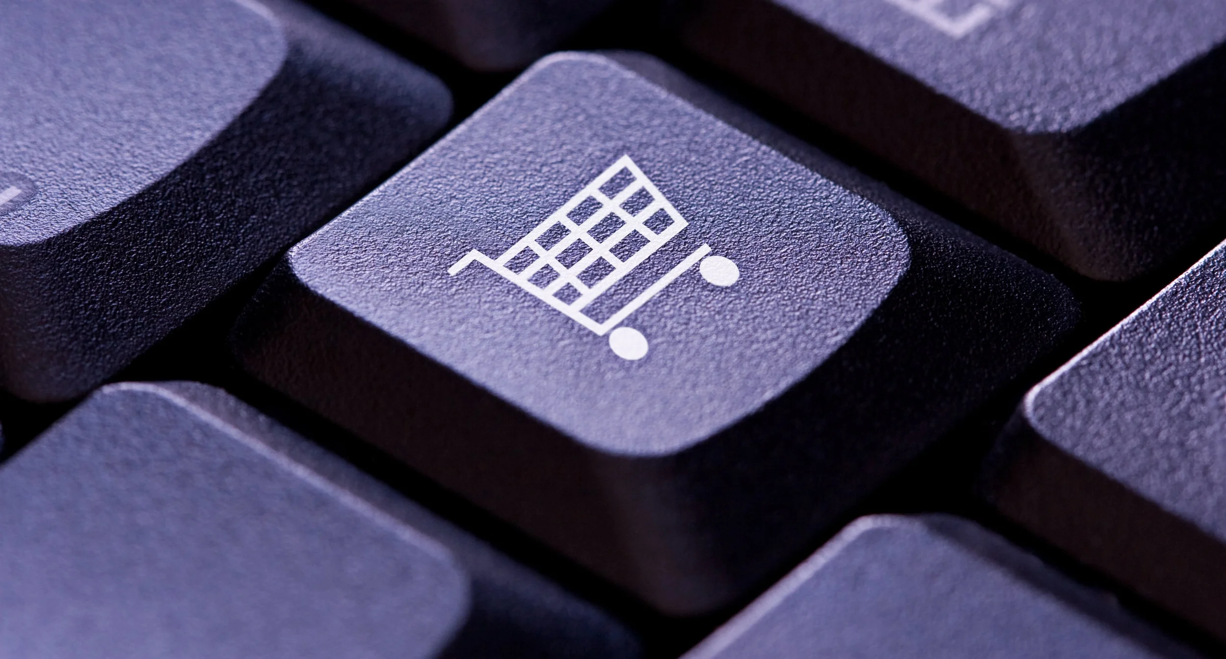Image; A purple keyboard, with the photo centered on one key which features the logo of a shopping cart. 