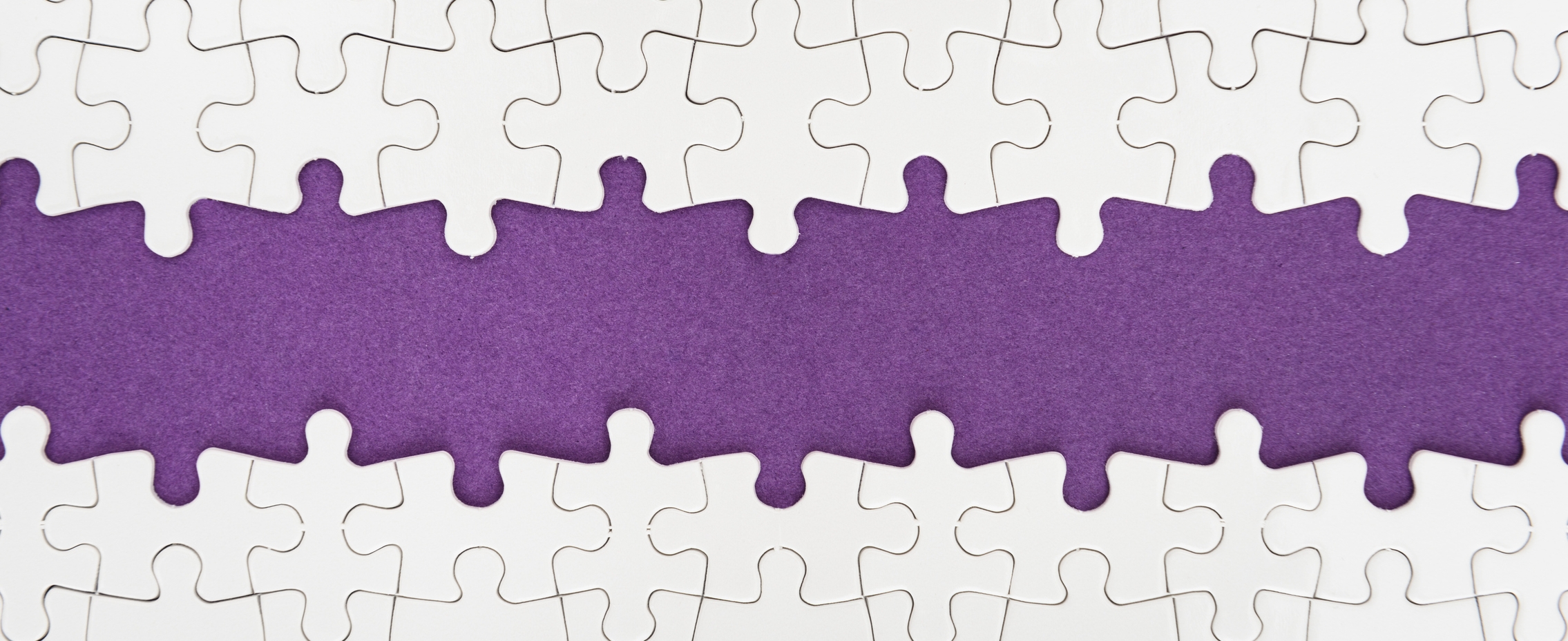 Image: White puzzle pieces missing connecting pieces in the middle. They are laying on purple felt. 