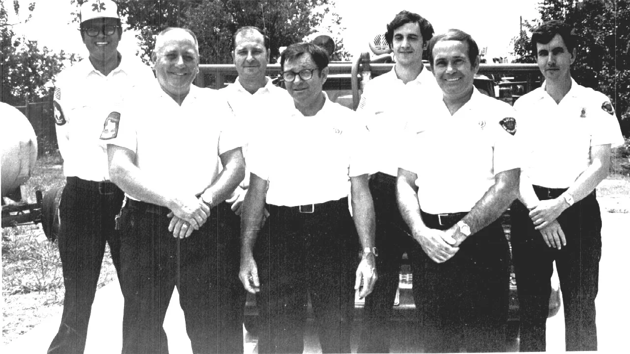Lee Bauer (center) with Chief Frank Hamlin (left of center) and other volunteer firefighters. Photo provided by Lucas FD.