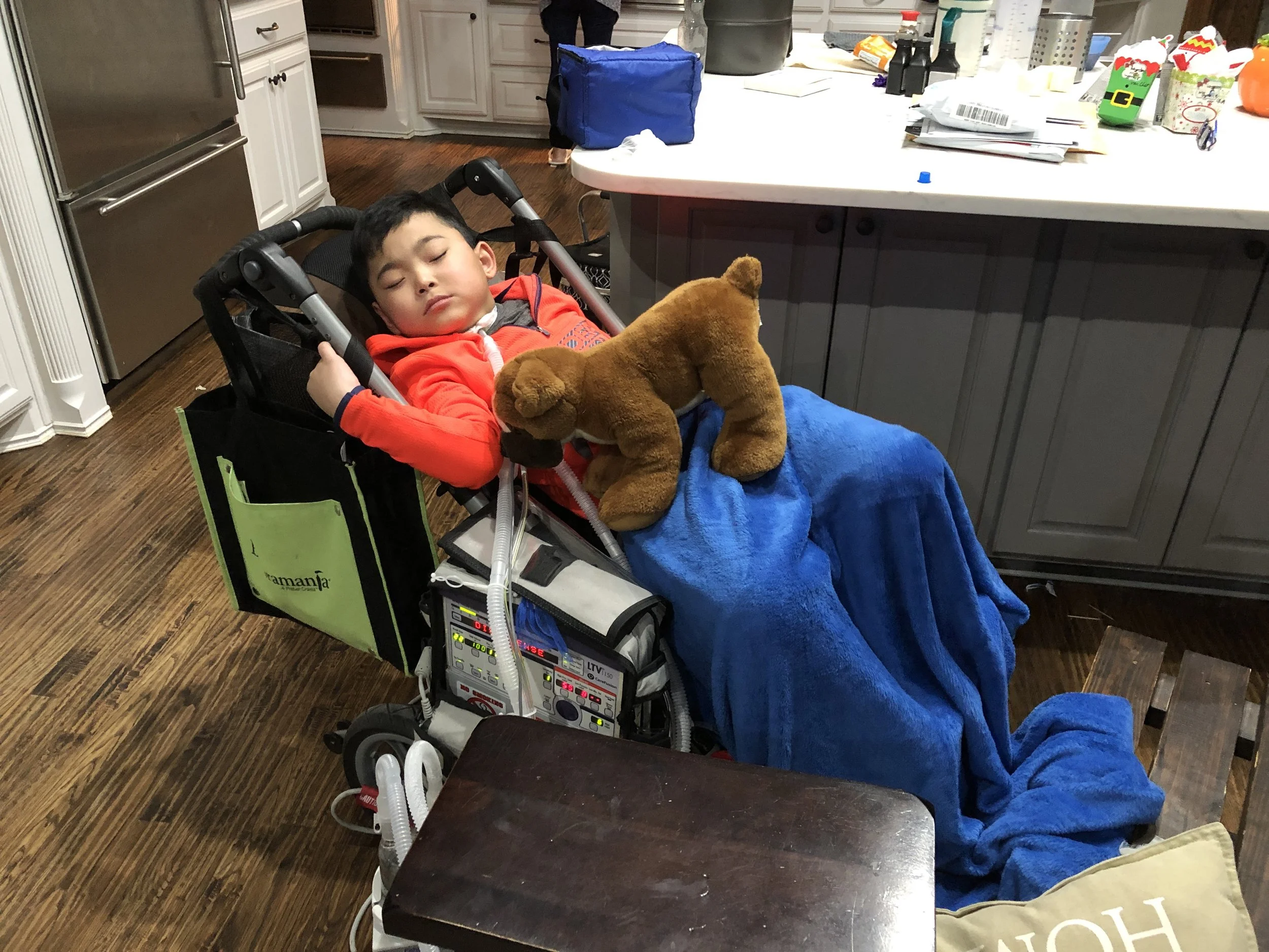 : Laynson rests at home after a day at school. This “stroller” is equipped with a ventilator and other emergency equipment. Each school day it goes to school with Laynson.