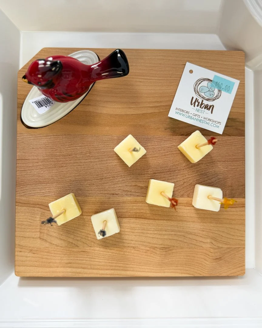 Decorative cardinal figurine on a wooden serving board with cheese cubes at Urban Nest