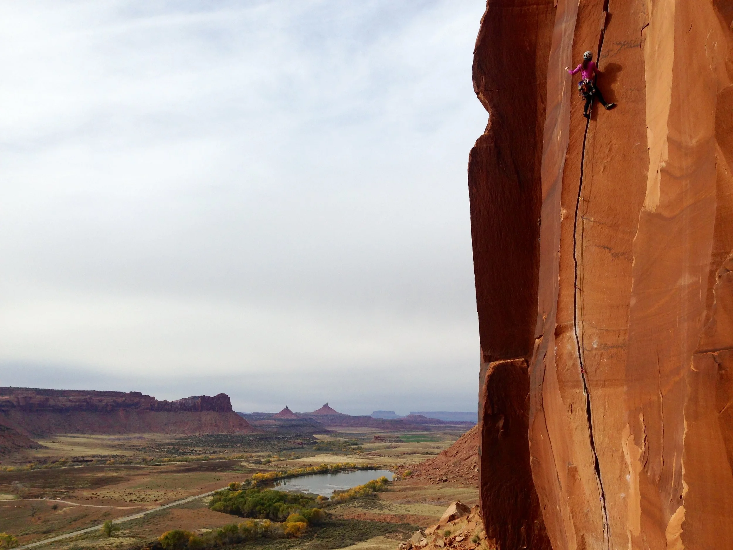 Erin climbing in Indian Creek, Utah, traditional territory of Navajo, Hopi, Zuni, Ute Mountain Ute, & Uintah Ouray Ute.