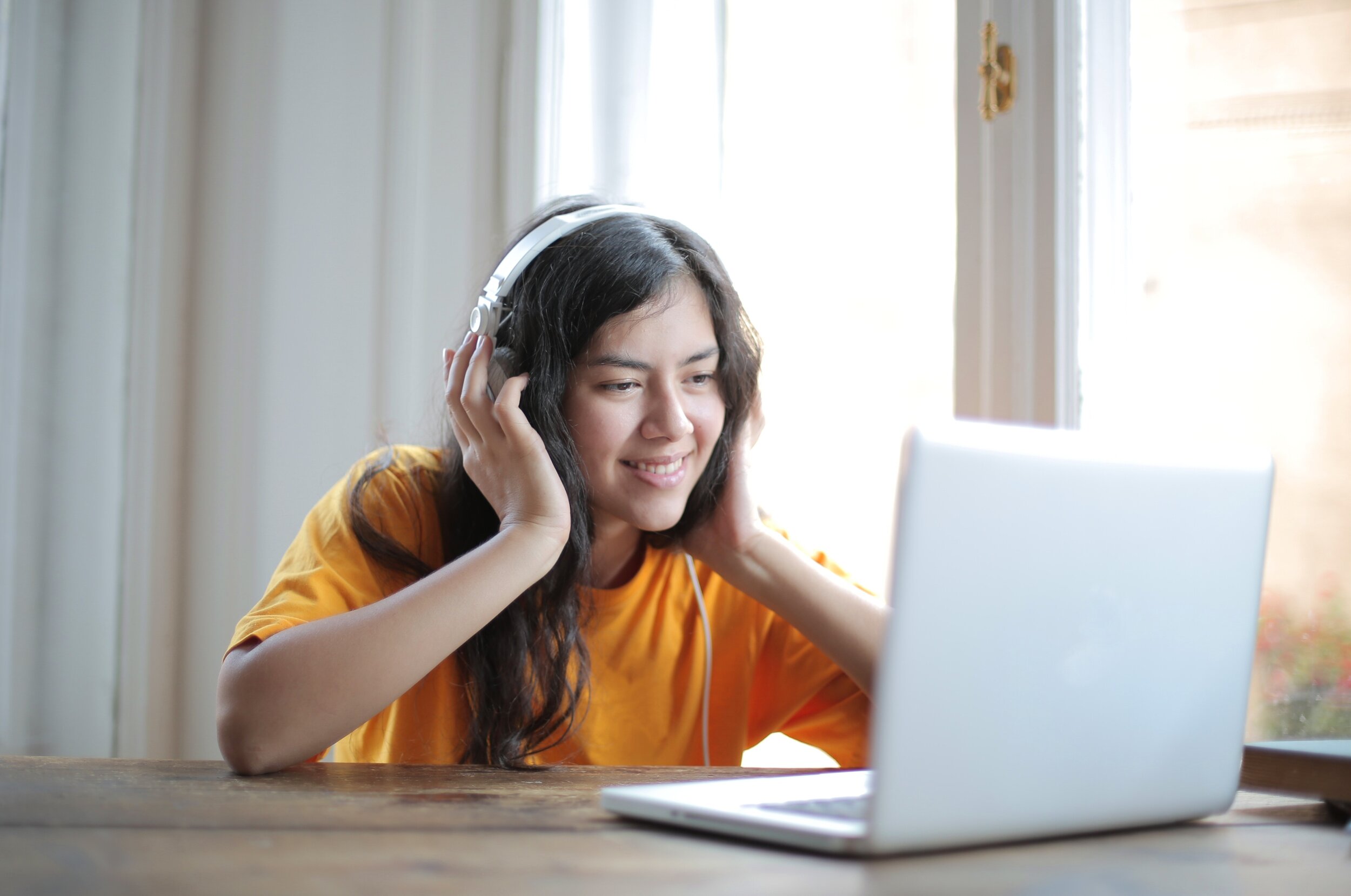 woman-in-orange-shirt-sitting-by-the-table-using-macbook-3808021.jpg