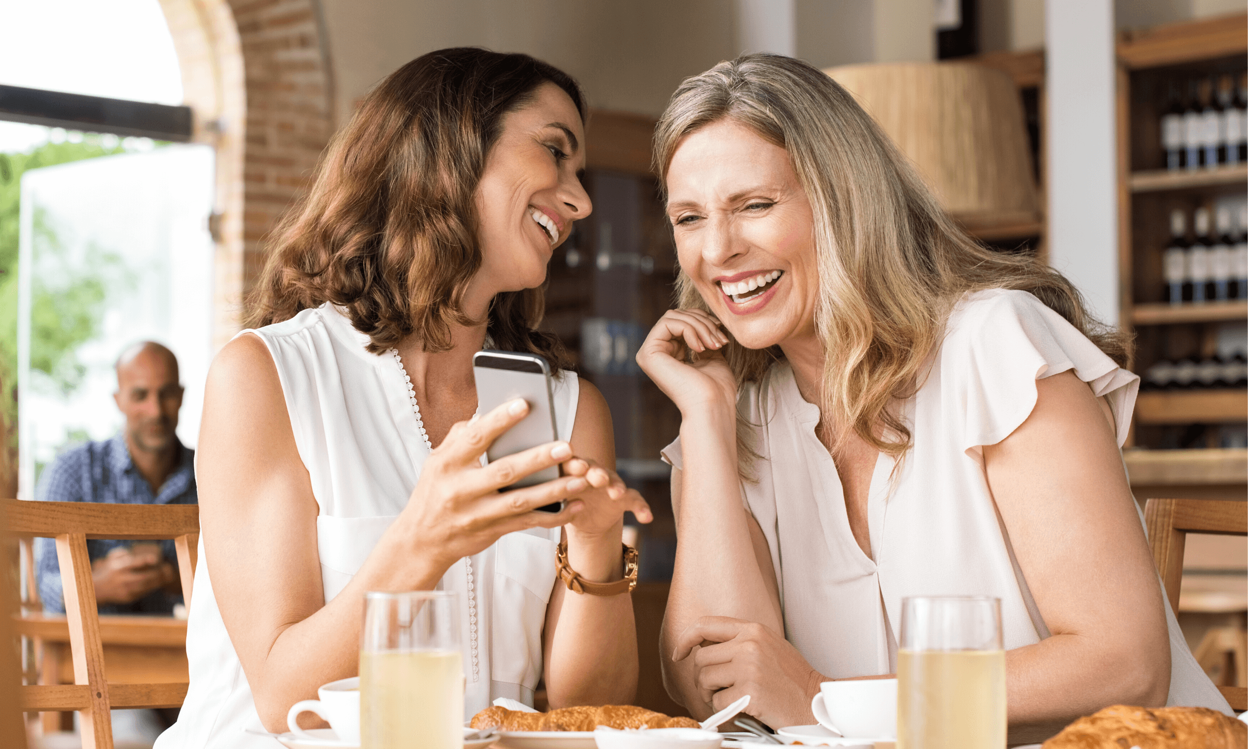 Gode venner på kafé som ser på en mobiltelefon