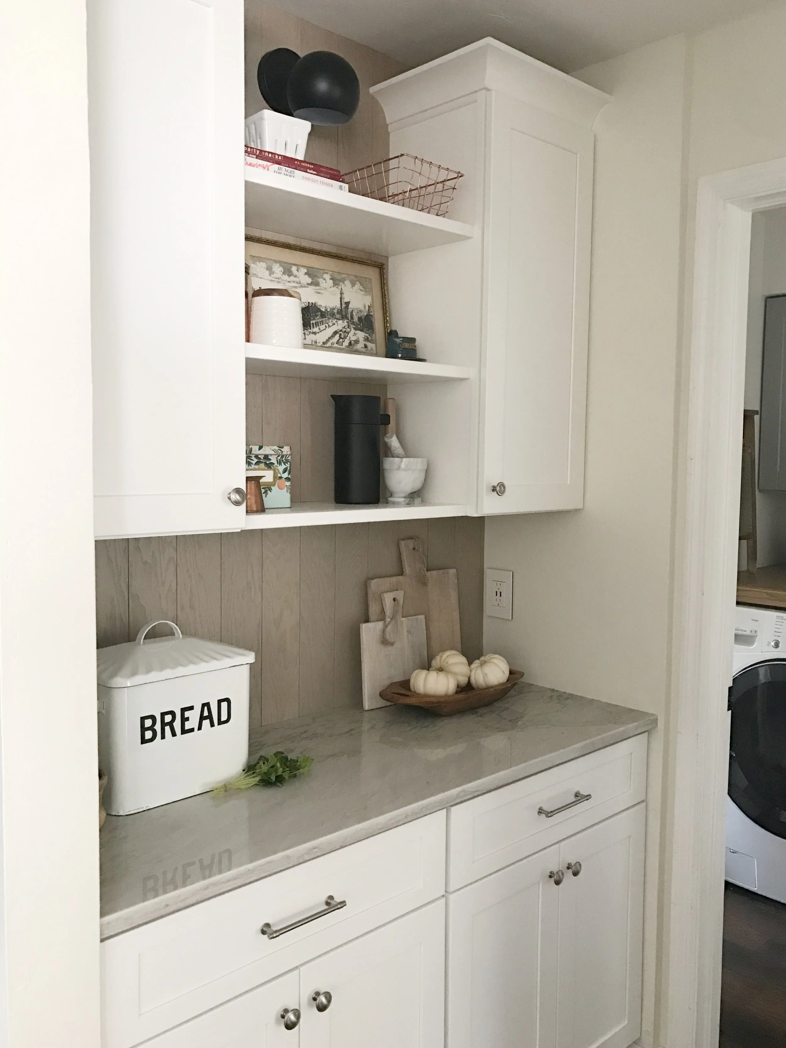 AFTER- pretty countertops and floating shelves replace a basic wire shelf pantry. I can’t believe its the same little space.