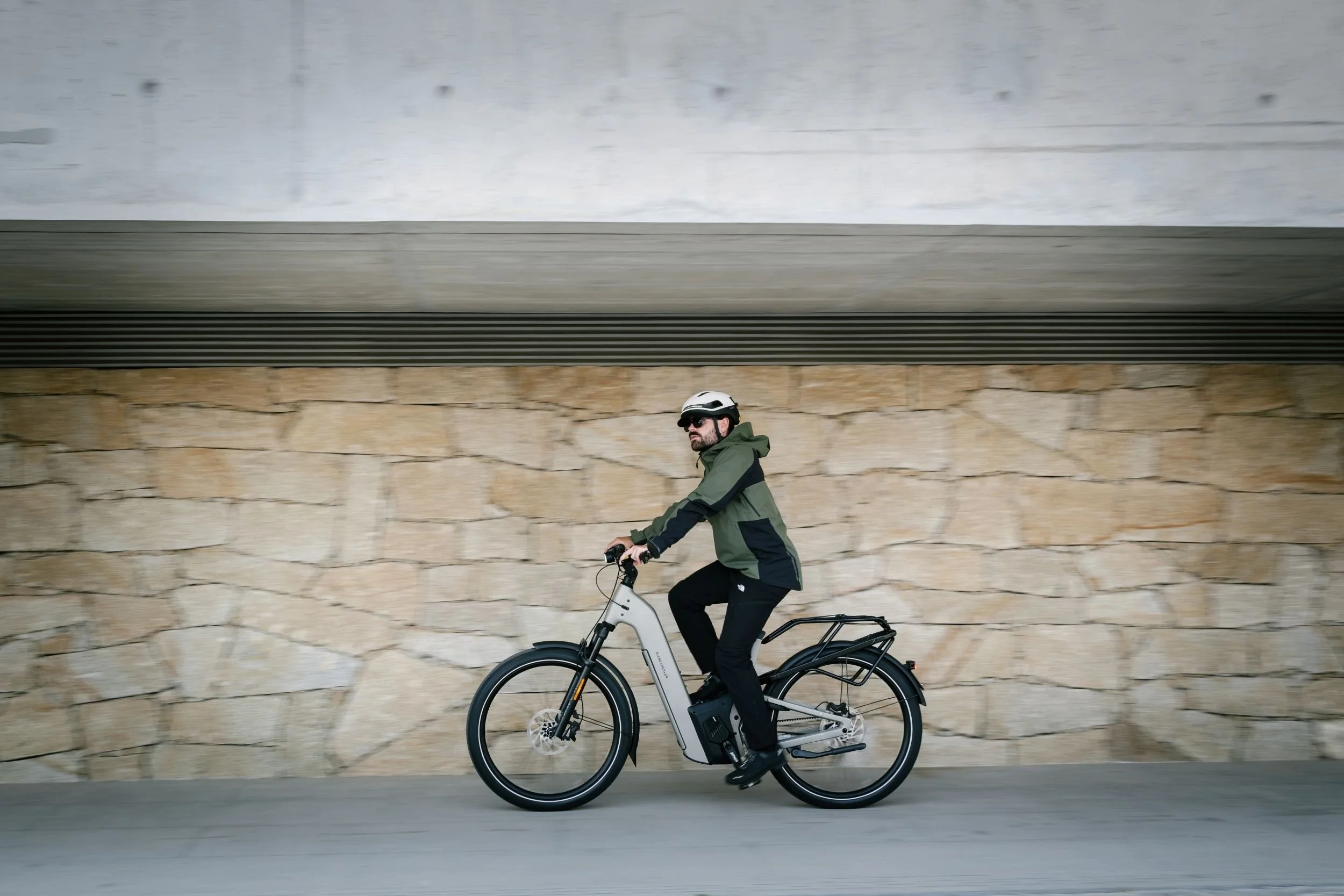 man in green jacket and black trousers riding a premium eletric bike fast