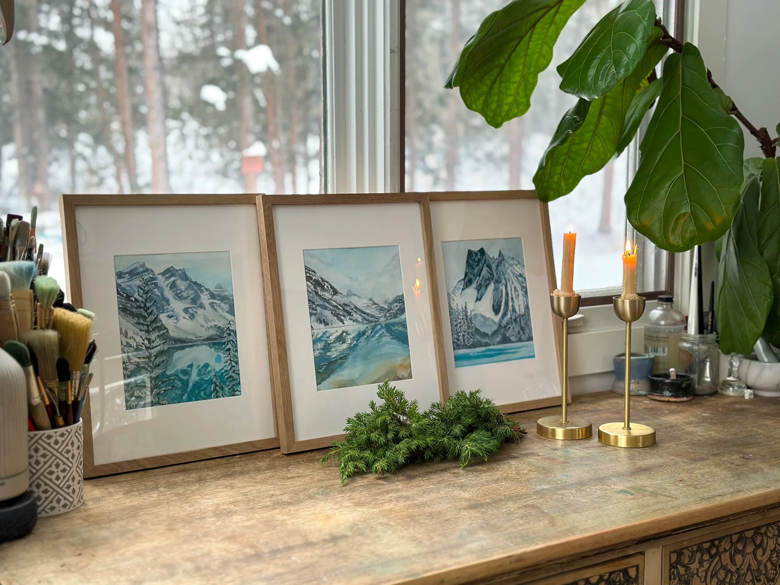 Winter Collection - Original Gouache Landscape Paintings inspired by Winter in the Canadian Rocky Mountains in a snowy window with lit candles