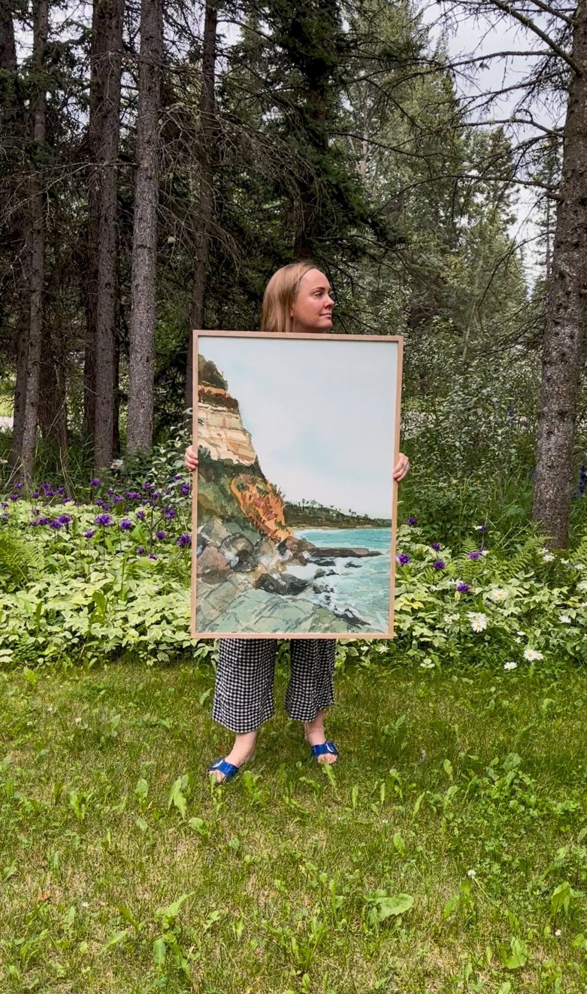 Swami’s Beach Art Print in 24×36” Framed held by Rebecca Sobbi in a forest backdrop