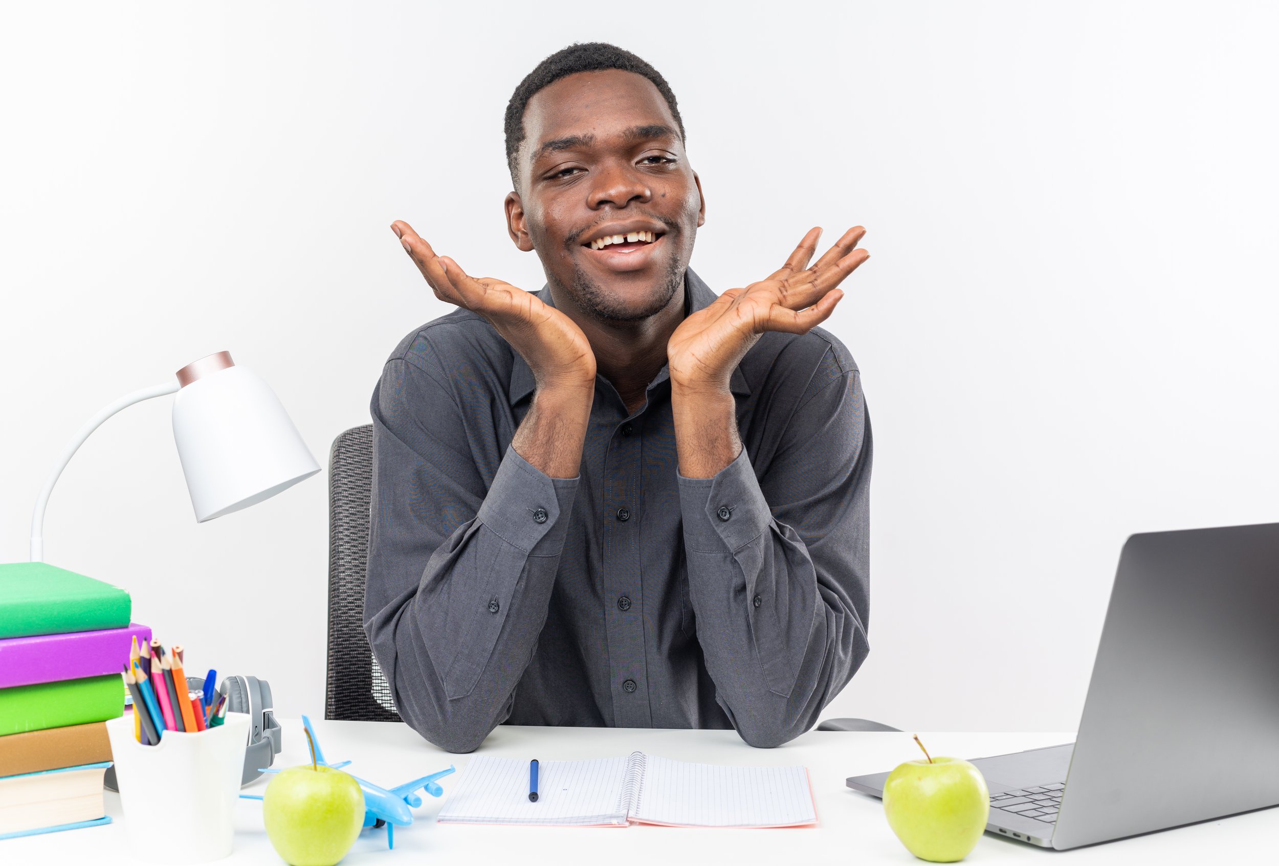 smiling-young-afro-american-student-sitting-desk-with-school-tools-keeping-hands-open.jpg