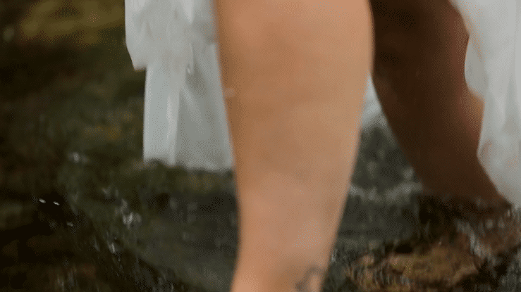 young couple roll around in the grass at sundown