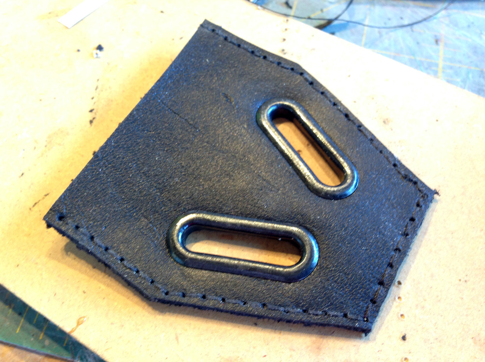  Shortly after, I decided to completely replace the entire piece at the bottom of the shoulder armor. I cut and stitched a new leather piece to replace the vinyl one, added accurate metal grommets and transplanted my accurate tabs. 