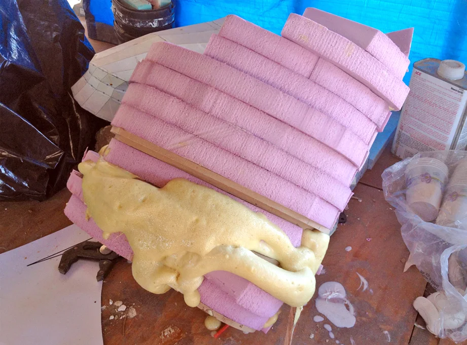 I cut sheets of pink insulation foam and spray glued them into the framework. Small areas were filled with Smooth-On Expanding Urethane foam. It expands gently, filling all pockets. The aerosol expanding foams as found in hardware stores is pretty aggressive, and can push pieces apart. It is also crazy sticky and takes forever to cure.