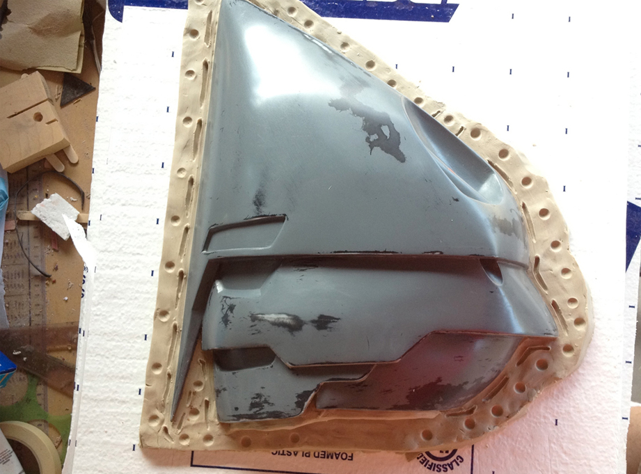  Now that everything was built and sanded smooth, it was time to make the mold of the helmet. I cut a hole the shape of the helmet’s profile in 2″ insulation foam and sealed the seam line with clay. 