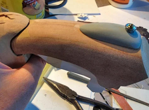 I carved some MDF to make the grip detail and added some metal hardware that looks similar to the reference.