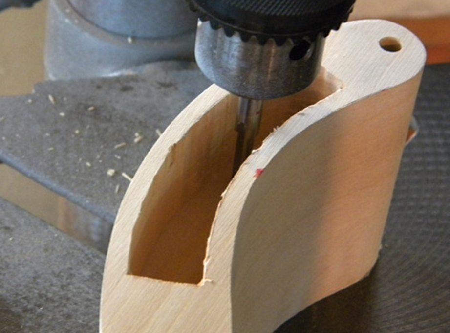  I put a router bit in the drill press and started cutting material out of the blade hole, removing 1/4″ of material with every pass. 