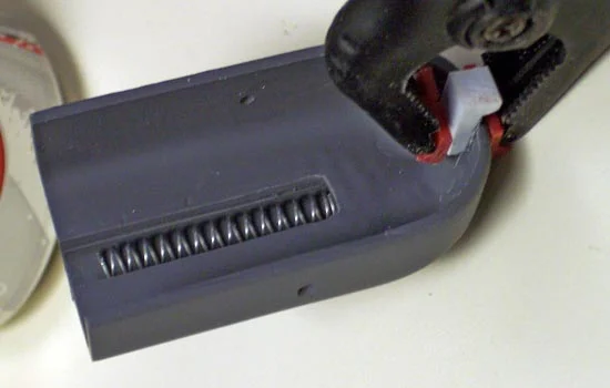 A “L” shaped piece was glued on to the end that will fit into a slot on the lower receiver. Note the spring in place.