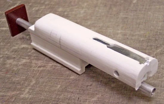 The bolt slides on the spring guide as shown. A spring will fit between the bolt and the brown piece to move the bolt forward.