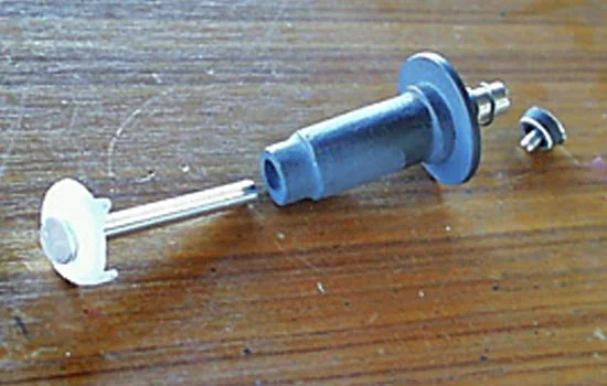 The center pin has a ratchet cap that holds the lid in place as well as allows the center spring to be wound. This was drill-lathed out of laminated plastic.