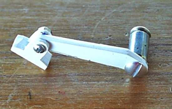 This swiveling roller arm attaches to the spring case to push the bullets out of the drum.