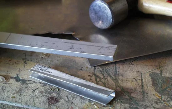 I formed the magazine release by hammering aluminum sheet around a steel bar.