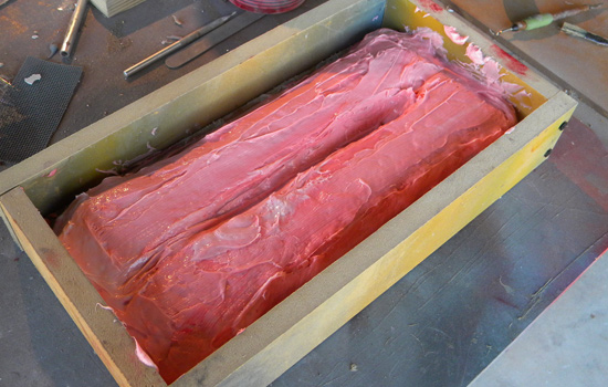 After the resin halves were completed, I placed them in a mold box and applied a thinned coat of Smooth-On MoldMax Stroke to capture detail. Once that cured, I applied a thick coat of Stoke to build the mold walls.