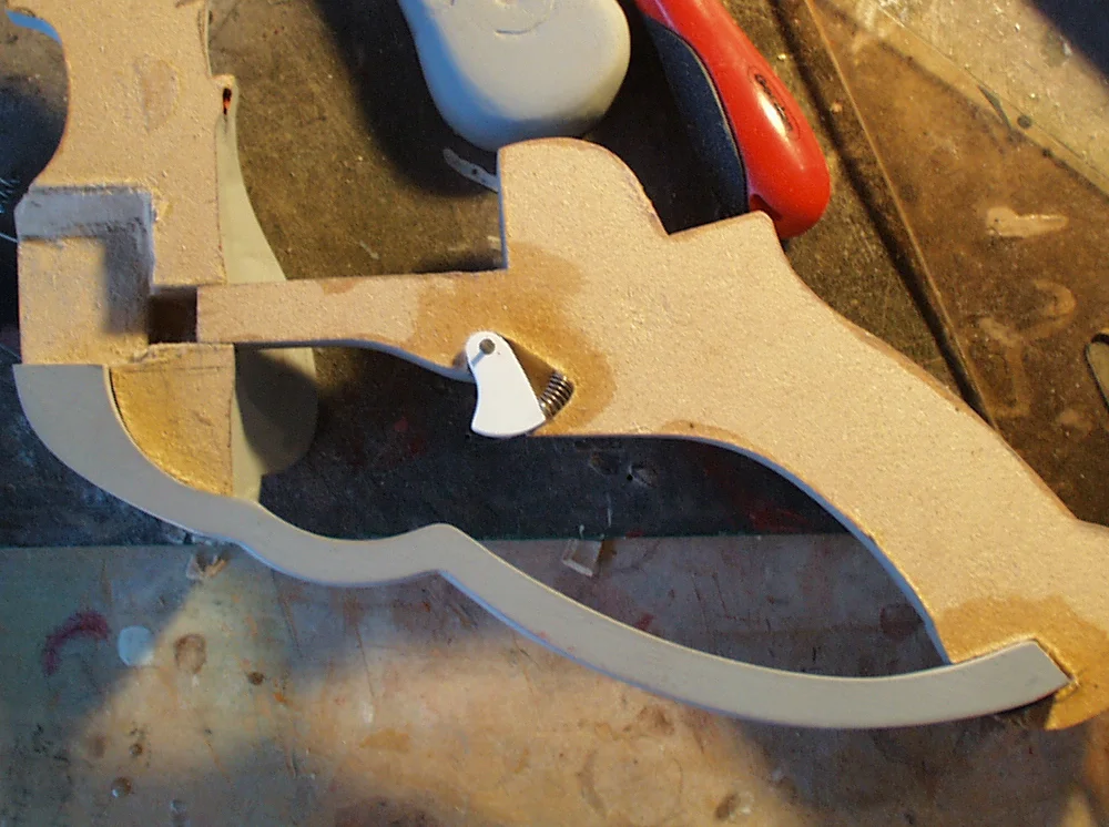 I hollowed out a recess for the trigger to operate.The trigger was cut from plastic, swivels on a nail and pushed forward by an ink pen spring.
