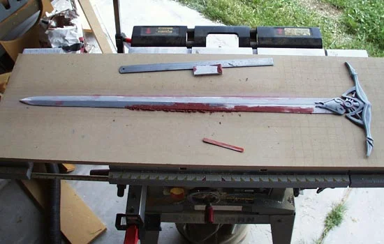 I made half of the blade from 1/4″ Poplar and glued it to a sheet of MDF. A resin copy of the hilt was also glued in place.