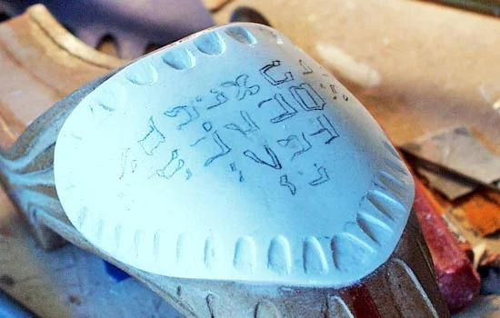 To make the shield, I heated a piece of styrene with a heat gun and molded it to fit. I attached it with Bondo and carved the edge scallops into the shield.